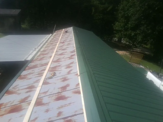 Old rusted panels beside newly installed green metal roofing — Wind Damage Roof Repair by Roofing Brothers in Mount Carroll