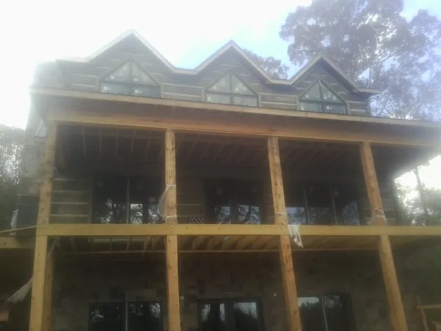 Dormers and porch framing on a large log home under construction — Roof Coating work by our crew in Mount Carroll
