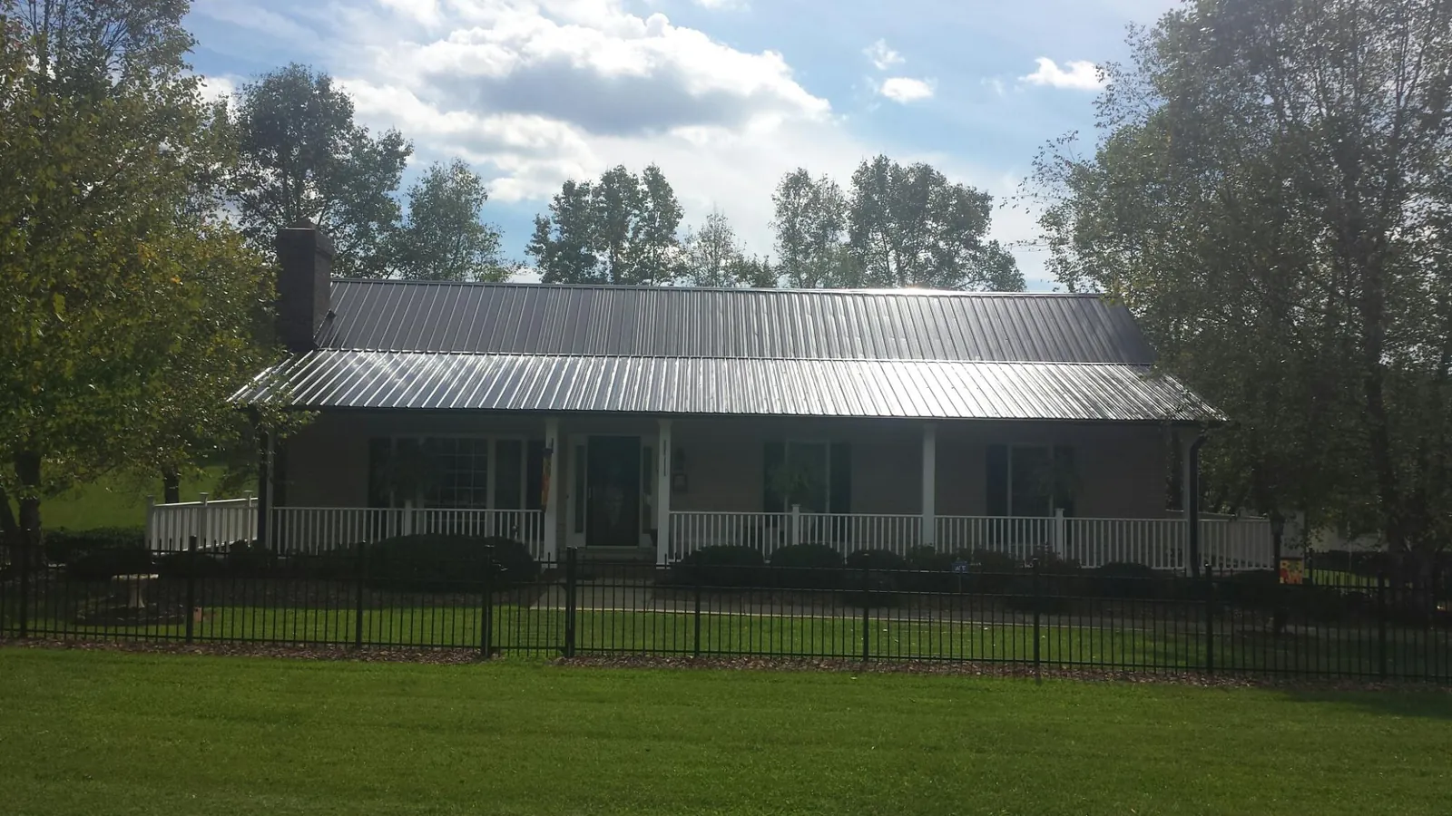 Gray metal roof on a brick ranch with a full width front porch — Gutter Guard Installation work by our crew in Mount Carroll