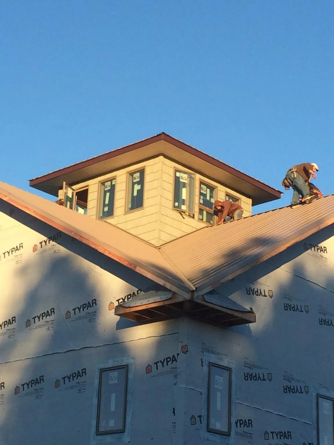 Roofers working around a rooftop cupola on a new metal roof at sunset — Roof Waterproofing in Mount Carroll by Roofing Brothers